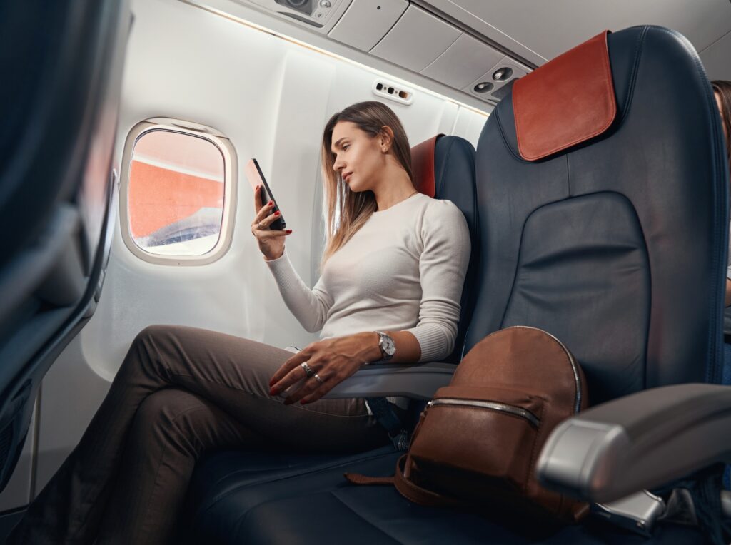 Passenger on plane flight looking at mobile phone