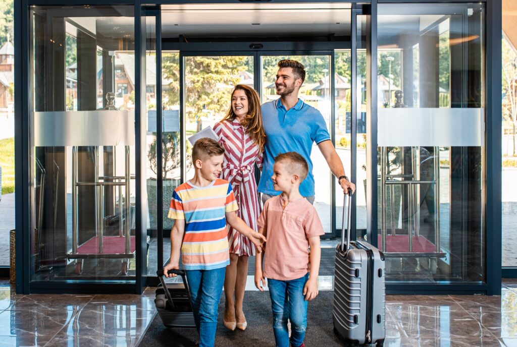 Smiling family of four in the hotel lobby check in at the reception for vacation.