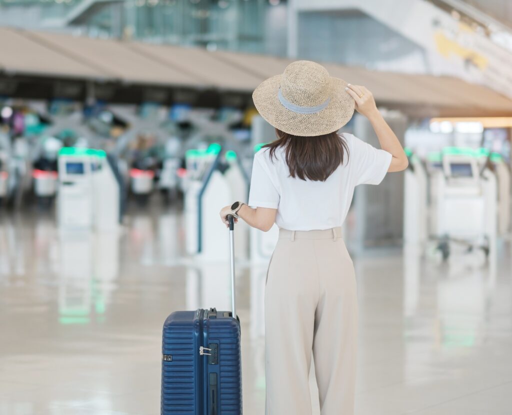 Young woman hand holding luggage handle before checking flight time in airport, Transport, insurance